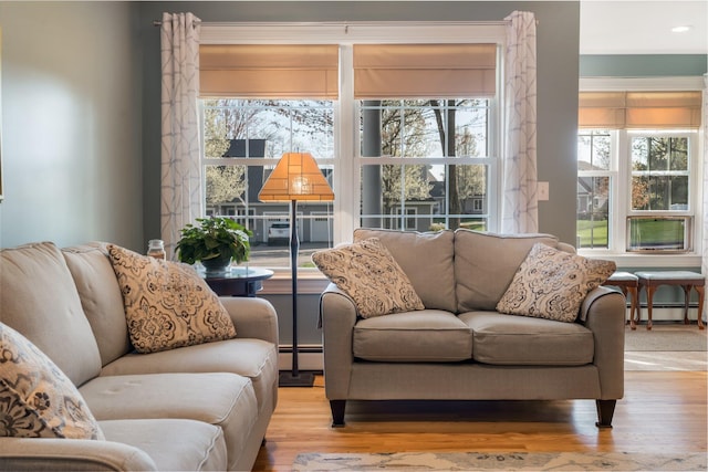 living area with a baseboard radiator, recessed lighting, a baseboard heating unit, ornamental molding, and wood finished floors