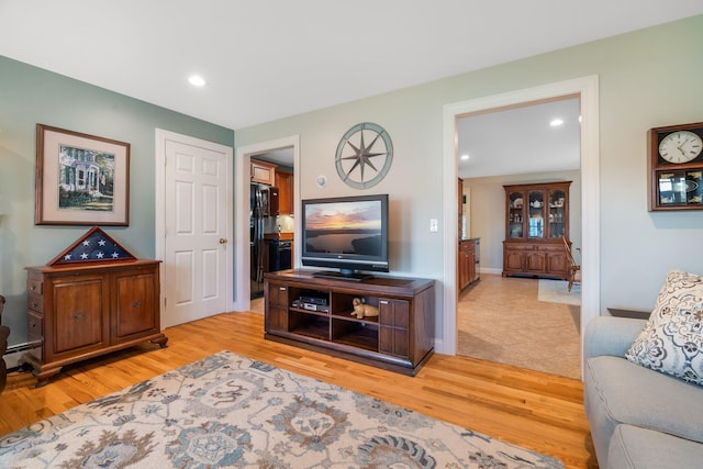 living room with recessed lighting, baseboard heating, and light wood-type flooring