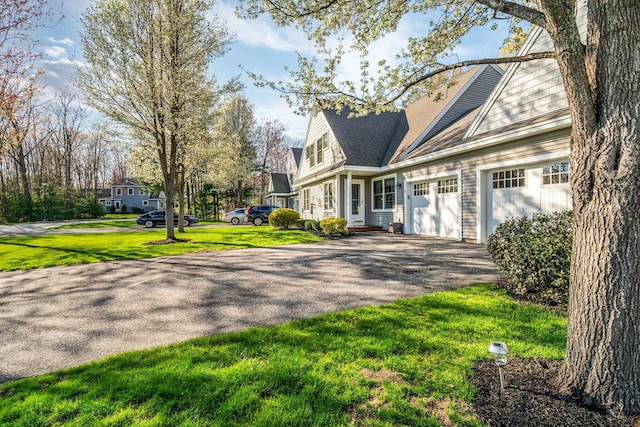 view of side of home featuring aphalt driveway, a garage, and a lawn