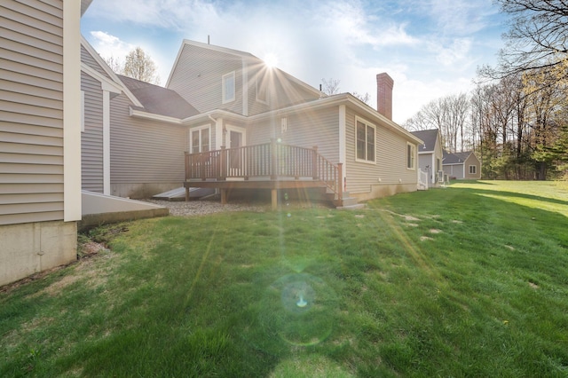 rear view of house with a yard, a deck, and a chimney