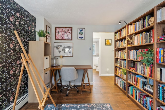 178 Bradley St, Saco, ME 04072 - office area featuring wood finished floors, baseboards, baseboard heating, wall of books, and a textured ceiling