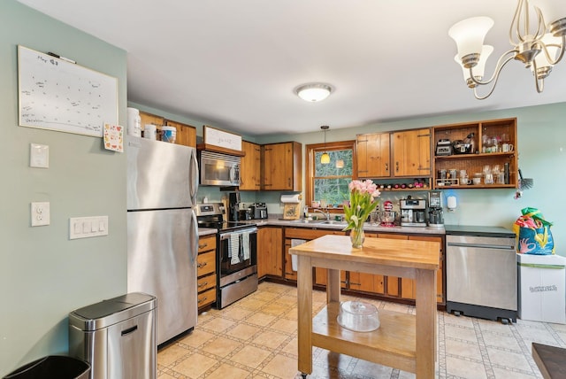 178 Bradley St, Saco, ME 04072 - kitchen with stainless steel appliances, a sink, hanging light fixtures, brown cabinets, and a chandelier