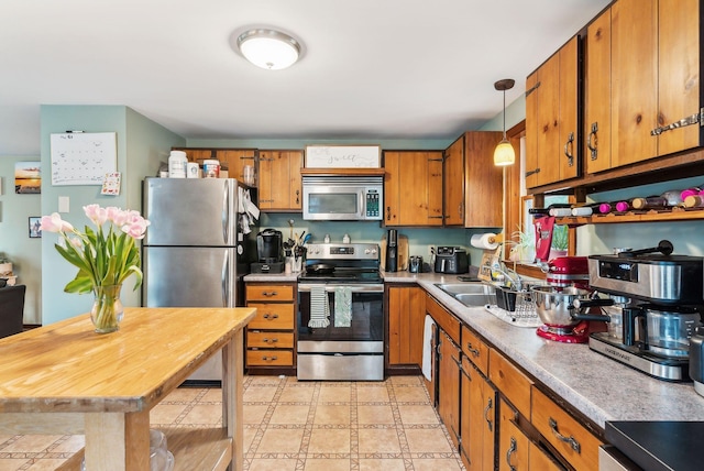178 Bradley St, Saco, ME 04072 - kitchen featuring appliances with stainless steel finishes, brown cabinets, a sink, light countertops, and hanging light fixtures