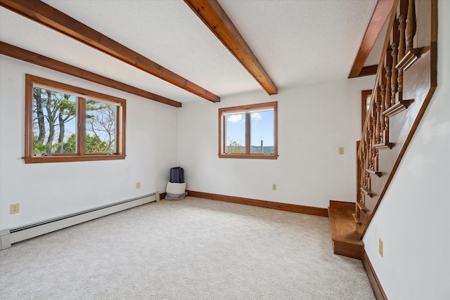 empty room featuring plenty of natural light, a baseboard radiator, light colored carpet, stairs, and beamed ceiling