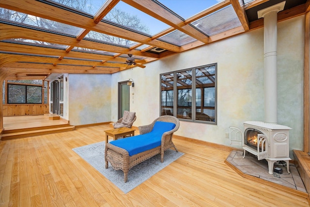 sitting room featuring coffered ceiling, wood finished floors, a skylight, a wood stove, and beam ceiling