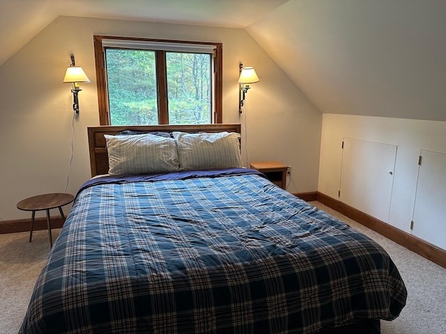 carpeted bedroom with vaulted ceiling and baseboards