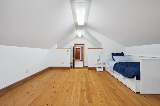 unfurnished bedroom with light wood finished floors, lofted ceiling, and baseboards