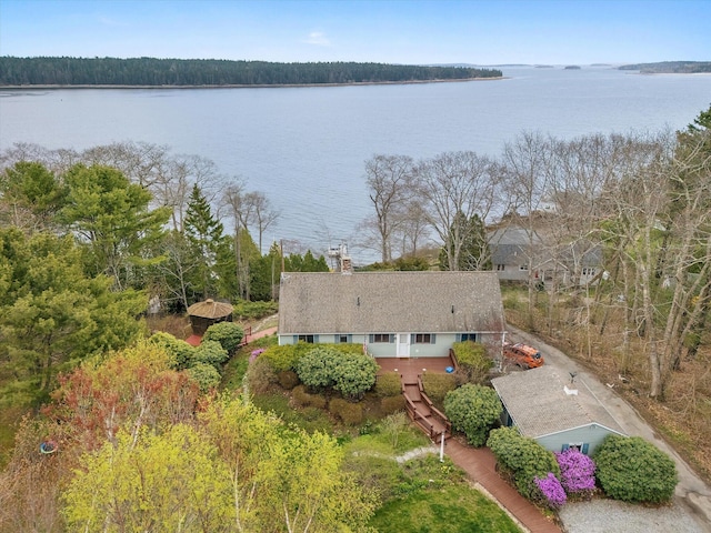 aerial view of property and surrounding area featuring a nearby body of water and a forest