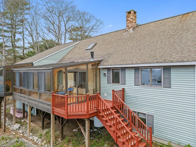 rear view of house with roof with shingles, a sunroom, a chimney, and stairway
