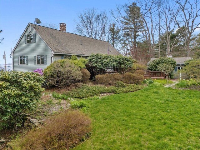 view of home's exterior featuring a chimney, a lawn, and roof with shingles