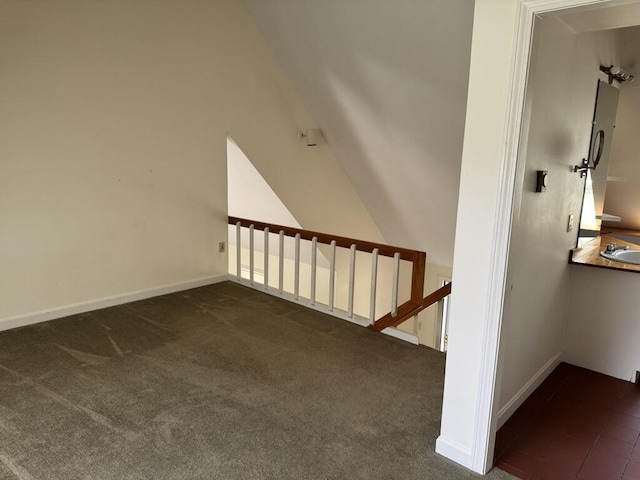 staircase with carpet flooring, baseboards, and lofted ceiling
