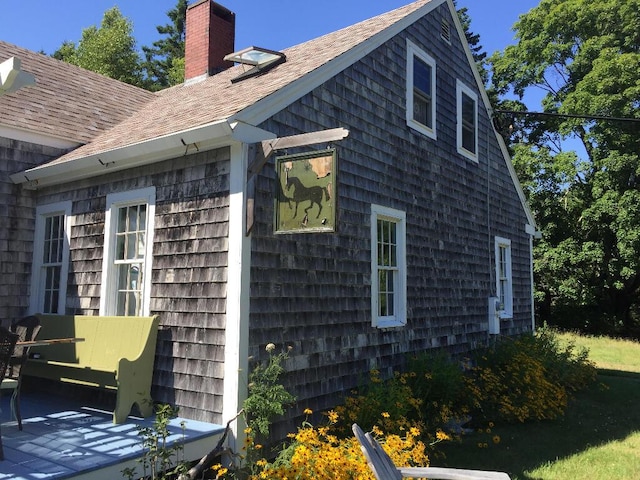 view of side of home with a chimney and roof with shingles