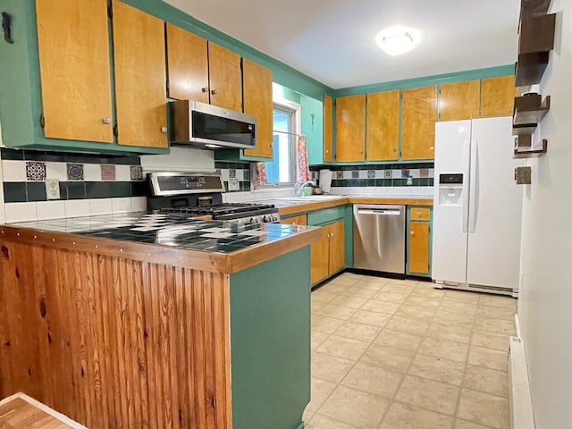 45 Seaview Ter, Belfast, ME 04915 - kitchen featuring appliances with stainless steel finishes, backsplash, brown cabinetry, light countertops, and a peninsula