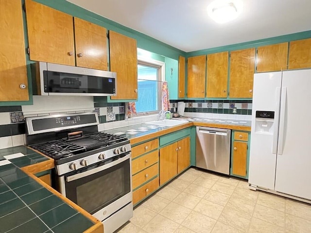 45 Seaview Ter, Belfast, ME 04915 - kitchen with stainless steel appliances, tile countertops, and brown cabinetry