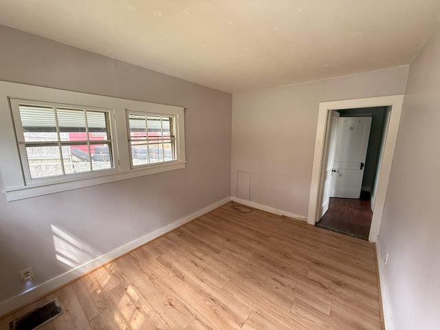 empty room featuring light wood finished floors and baseboards