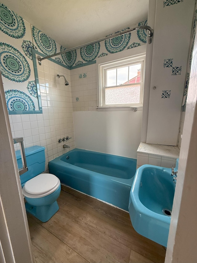 full bathroom with wood finished floors, shower / washtub combination, tile walls, toilet, and a sink
