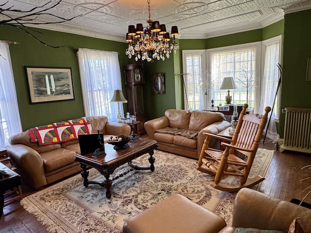 17 Boynton St, Eastport, ME 04631 - living room featuring radiator heating unit, an ornate ceiling, ornamental molding, wood-type flooring, and a chandelier