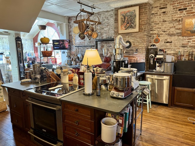 17 Boynton St, Eastport, ME 04631 - kitchen with stainless steel appliances, wood-type flooring, healthy amount of natural light, a sink, and brick wall