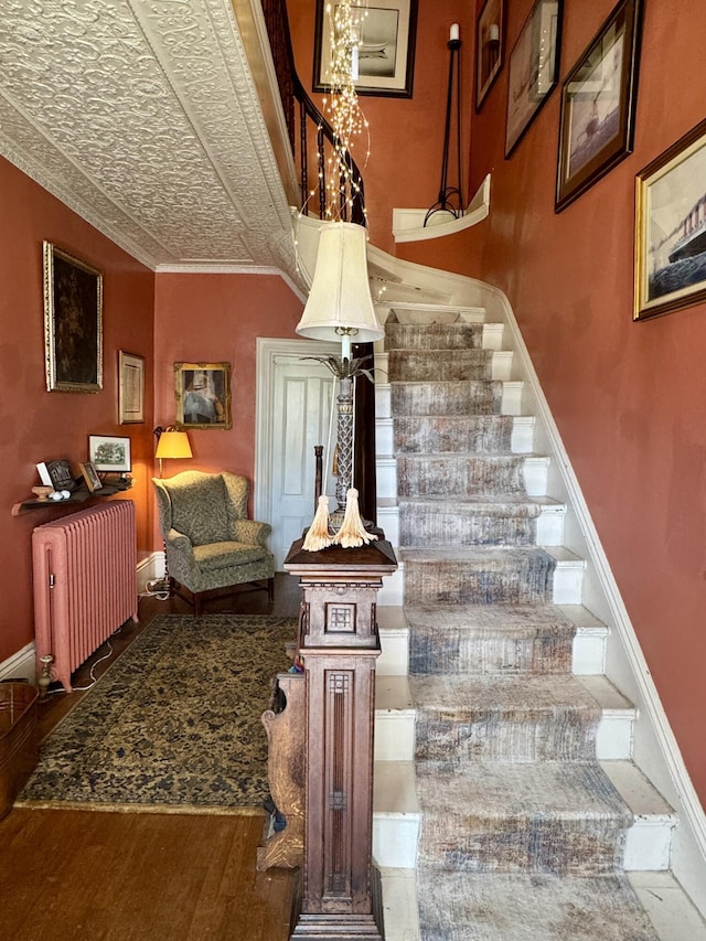 17 Boynton St, Eastport, ME 04631 - stairs featuring radiator heating unit, a chandelier, wood finished floors, baseboards, and ornamental molding