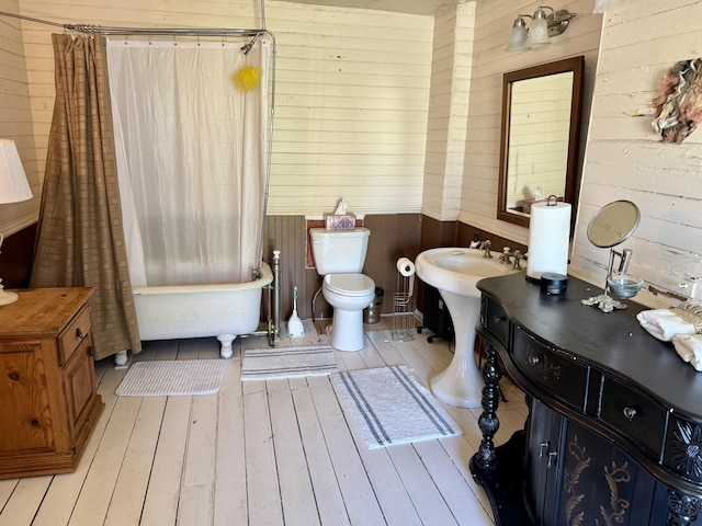 17 Boynton St, Eastport, ME 04631 - bathroom featuring hardwood / wood-style flooring, wood walls, toilet, wainscoting, and shower / bath combo