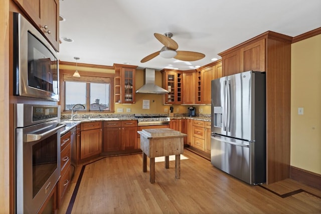 47 Atlantic Ave, Boothbay Harbor, ME 04538 - kitchen with wall chimney range hood, brown cabinets, ceiling fan, appliances with stainless steel finishes, and light stone countertops