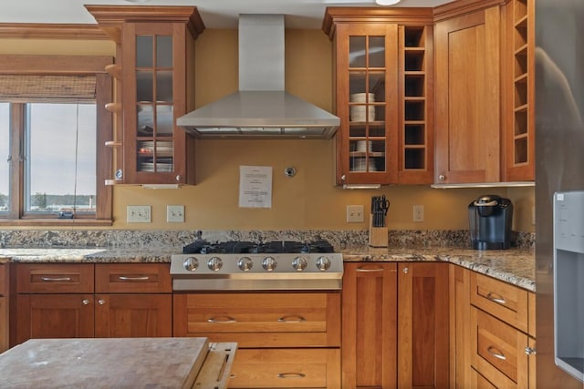 47 Atlantic Ave, Boothbay Harbor, ME 04538 - kitchen with wall chimney range hood, light stone counters, stainless steel gas cooktop, and brown cabinetry
