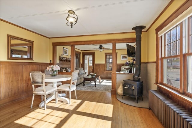 47 Atlantic Ave, Boothbay Harbor, ME 04538 - dining room with radiator heating unit, a wainscoted wall, a wood stove, and light wood-type flooring