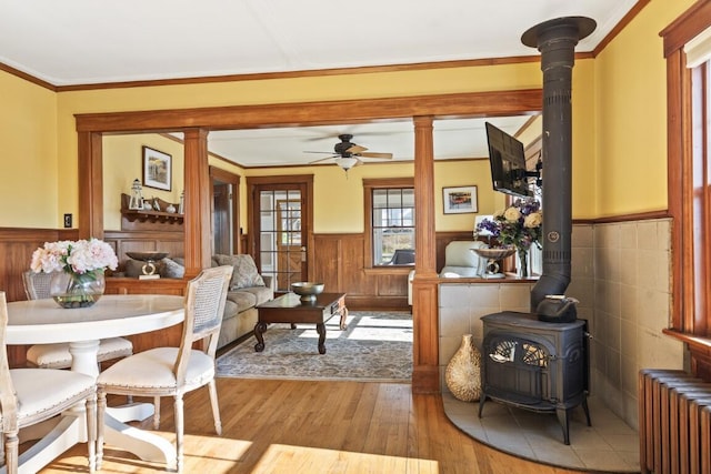 47 Atlantic Ave, Boothbay Harbor, ME 04538 - dining room featuring a wood stove, radiator, wainscoting, wood finished floors, and a ceiling fan