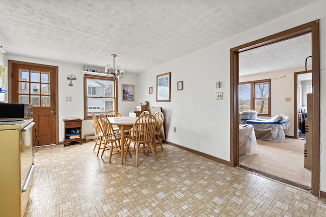 dining space featuring a textured ceiling, a chandelier, and baseboards