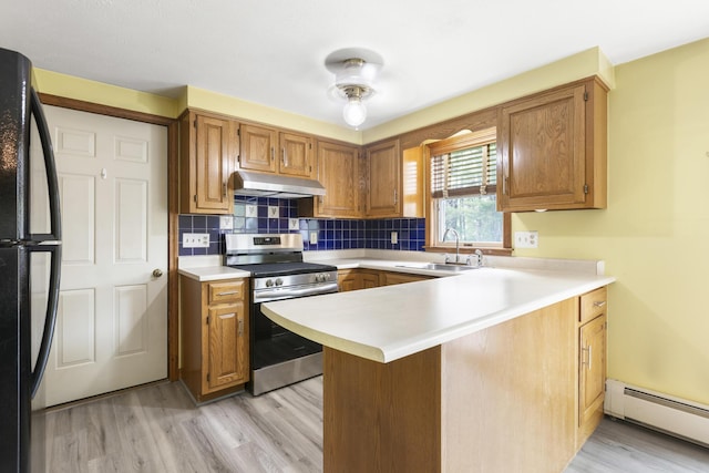 84 Old Carriage Rd Unit 84, Auburn, ME 04210 - kitchen featuring stainless steel electric range oven, a baseboard radiator, under cabinet range hood, freestanding refrigerator, and light wood-style flooring