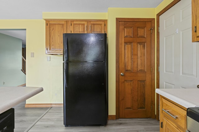 84 Old Carriage Rd Unit 84, Auburn, ME 04210 - kitchen featuring freestanding refrigerator, light wood-style floors, light countertops, brown cabinetry, and range