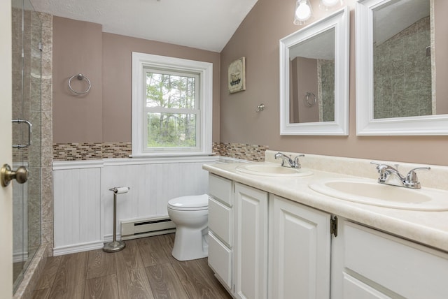 84 Old Carriage Rd Unit 84, Auburn, ME 04210 - bathroom featuring double vanity, a baseboard radiator, a tile shower, vaulted ceiling, and wood finished floors