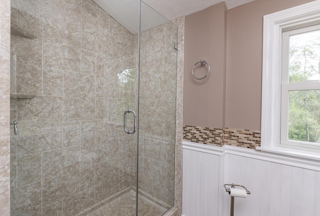 84 Old Carriage Rd Unit 84, Auburn, ME 04210 - bathroom featuring a stall shower, a wainscoted wall, a textured ceiling, and a decorative wall