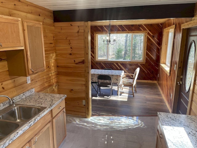 144 Redneck Rd, Starks, ME 04911 - kitchen featuring a sink, a chandelier, wood walls, dark wood-style flooring, and light stone countertops