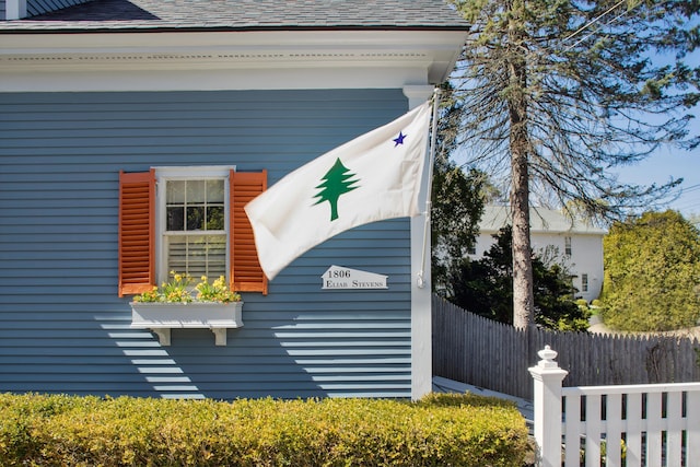 view of home's exterior with fence and a shingled roof
