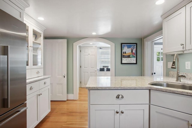 kitchen featuring white cabinetry, a sink, high end fridge, recessed lighting, and light wood-style flooring