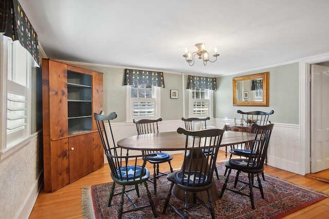 dining area featuring crown molding, a chandelier, and light wood-style flooring