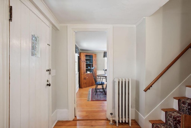 foyer featuring radiator, baseboards, light wood-type flooring, and stairs
