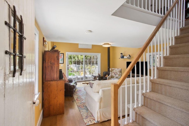 living area with wood-type flooring, baseboards, and stairway