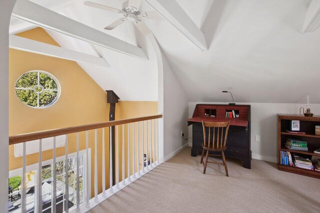 carpeted home office with a ceiling fan, baseboards, and lofted ceiling with beams