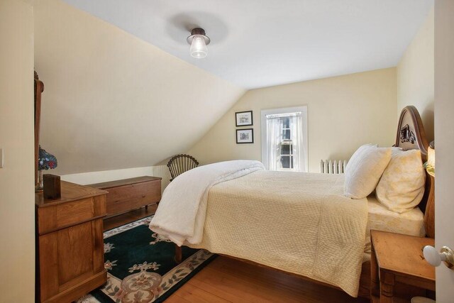 bedroom with wood finished floors and lofted ceiling