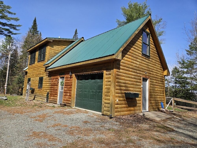 view of property exterior with a garage, driveway, metal roof, and log veneer siding