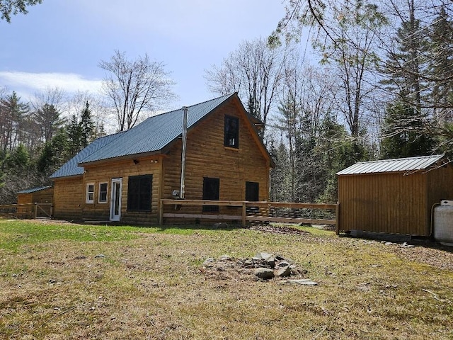 view of property exterior with an outdoor structure, fence, a shed, metal roof, and a yard