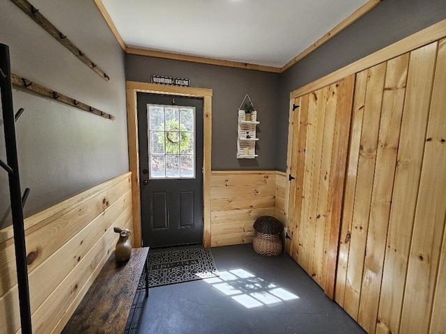 entryway featuring finished concrete flooring, a wainscoted wall, and wood walls