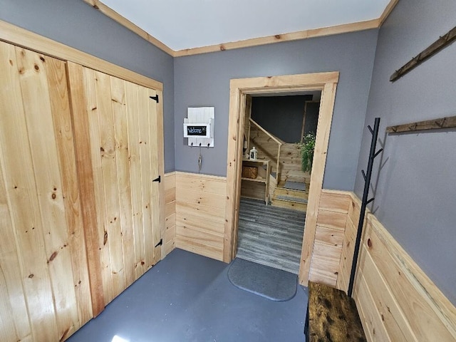 corridor featuring concrete flooring and wainscoting