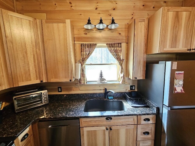 kitchen with a sink, dark stone counters, light brown cabinets, and stainless steel appliances