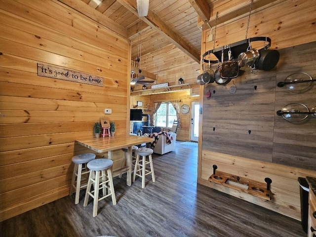 dining space featuring wood finished floors, wooden walls, wooden ceiling, and beamed ceiling