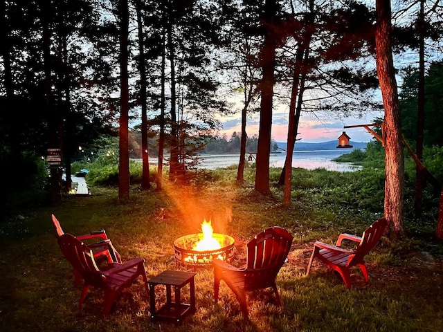 yard at dusk with a water view and an outdoor fire pit
