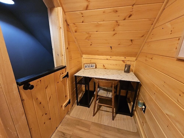 interior space featuring light wood-style floors, vaulted ceiling, and wood walls