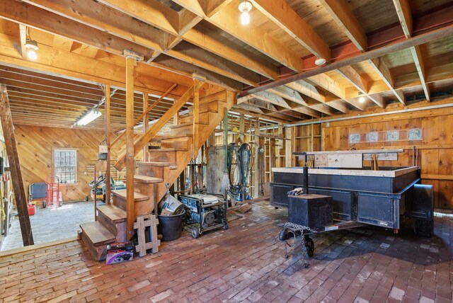 33 Smith Rd, Hallowell, ME 04347 - below grade area featuring a wood stove, wood walls, brick floor, and stairs